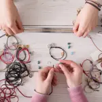 Icône Fait main avec des mains fabriquant des bijoux en fils et perles – Fil Dé Toile